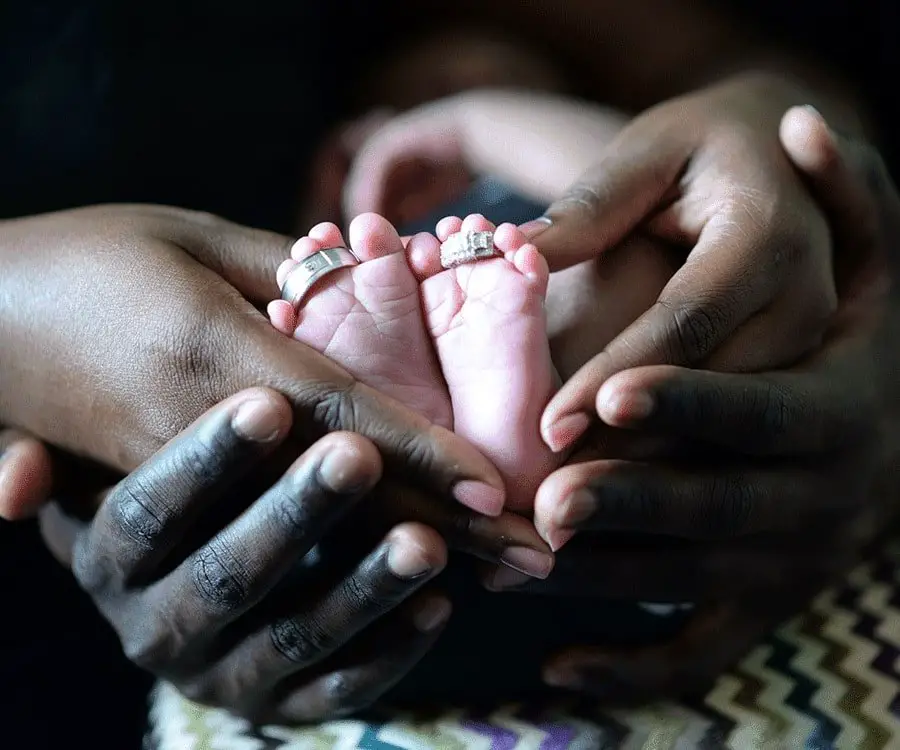 Hands of some parents holding their newborn baby